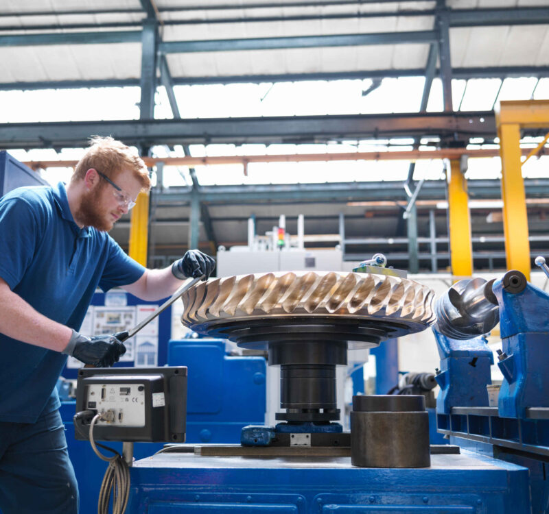 Engineer finishing bronze gear wheel in engineering factory